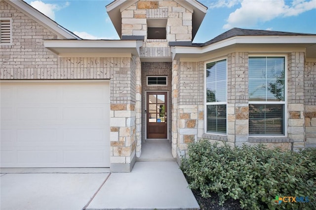 property entrance with driveway, stone siding, and a garage