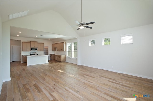 unfurnished living room featuring light wood-style flooring, visible vents, a ceiling fan, and a wealth of natural light