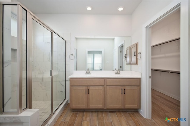 bathroom featuring a shower stall, wood finished floors, and a sink