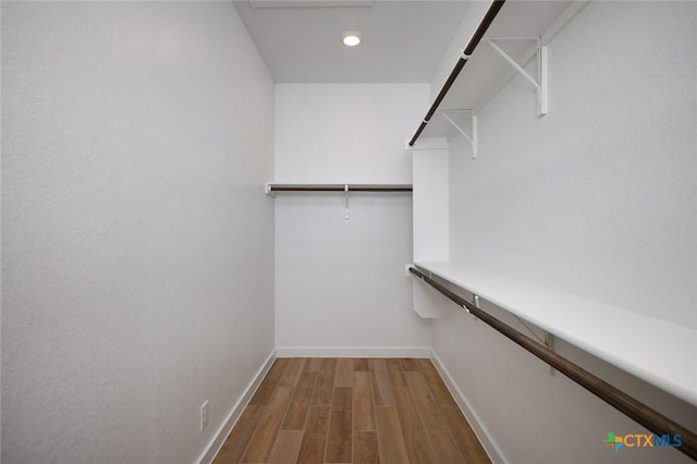 walk in closet with wood finished floors