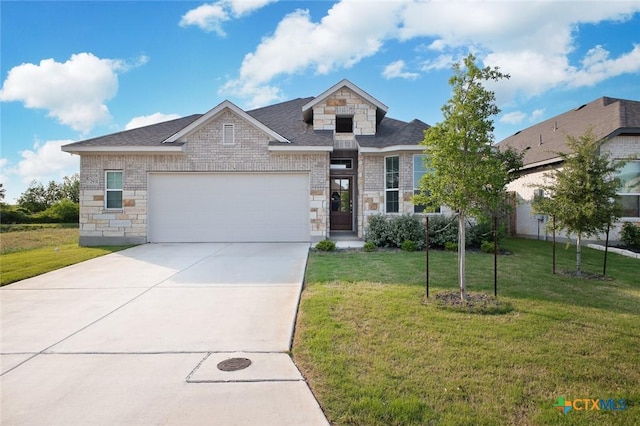 view of front of home featuring an attached garage, driveway, stone siding, and a front yard