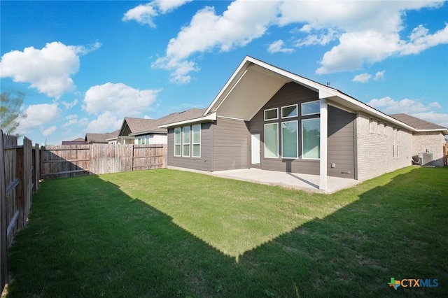 rear view of property with a lawn, brick siding, a patio area, and a fenced backyard