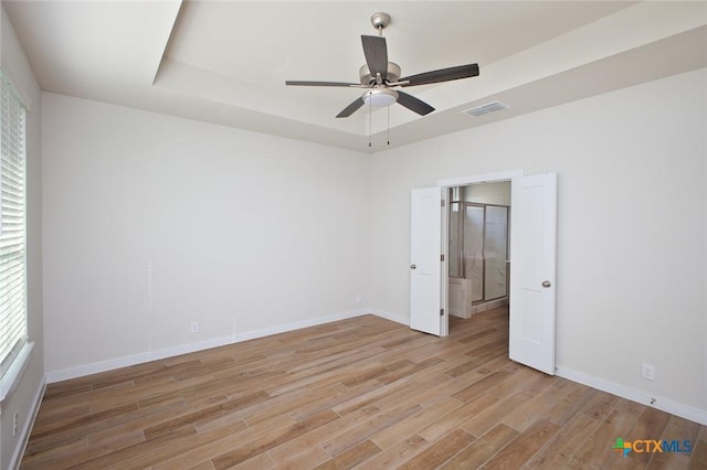 spare room with light wood-style flooring, visible vents, a ceiling fan, and baseboards