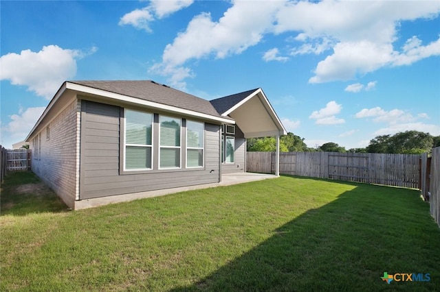 rear view of property featuring brick siding, a yard, a fenced backyard, and a patio