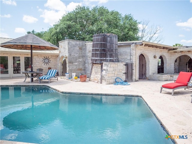 outdoor pool with french doors and a patio area
