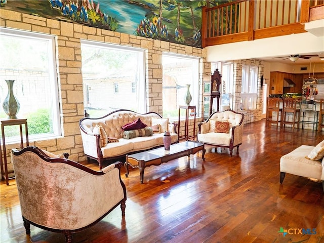 living room with hardwood / wood-style floors, ceiling fan, and a towering ceiling