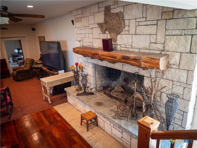 living area with wood-type flooring, ceiling fan, and a fireplace