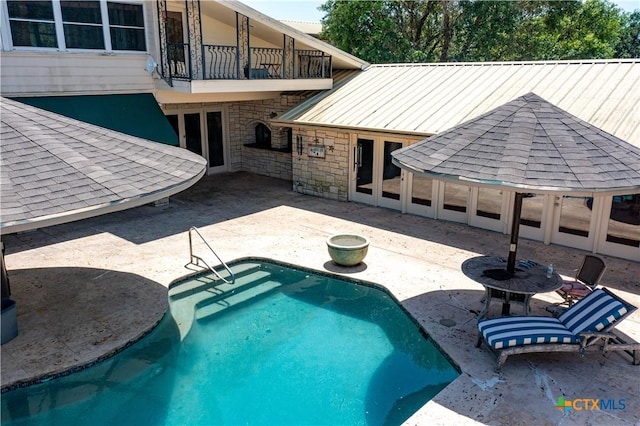 pool with french doors, a gazebo, and a patio