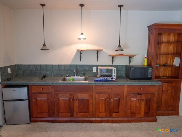 kitchen with brown cabinets, a sink, fridge, and black microwave