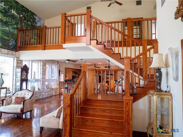 staircase featuring visible vents, ceiling fan, high vaulted ceiling, and wood finished floors