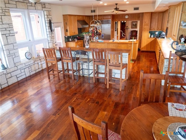 kitchen featuring visible vents, dark wood-style flooring, a sink, a ceiling fan, and under cabinet range hood
