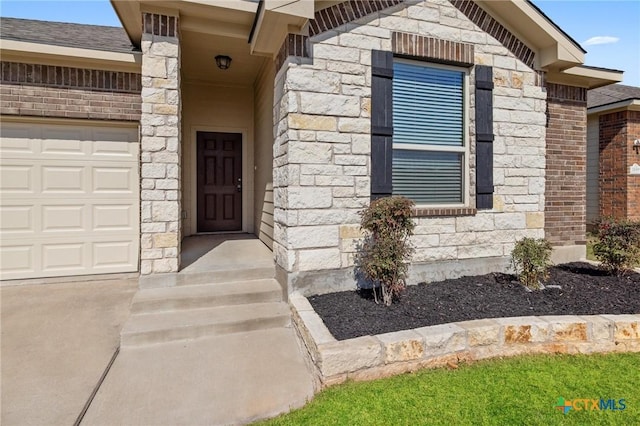 doorway to property with brick siding, stone siding, and an attached garage