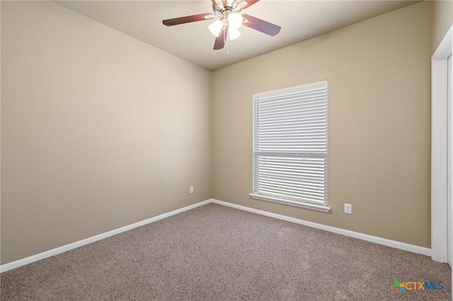 carpeted spare room with a ceiling fan and baseboards