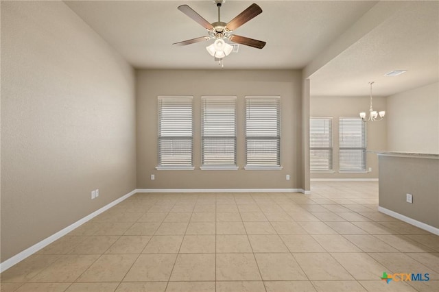 empty room with light tile patterned floors, visible vents, baseboards, and ceiling fan with notable chandelier