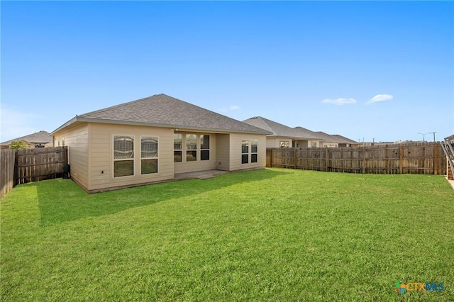 back of house featuring a yard, a fenced backyard, and roof with shingles