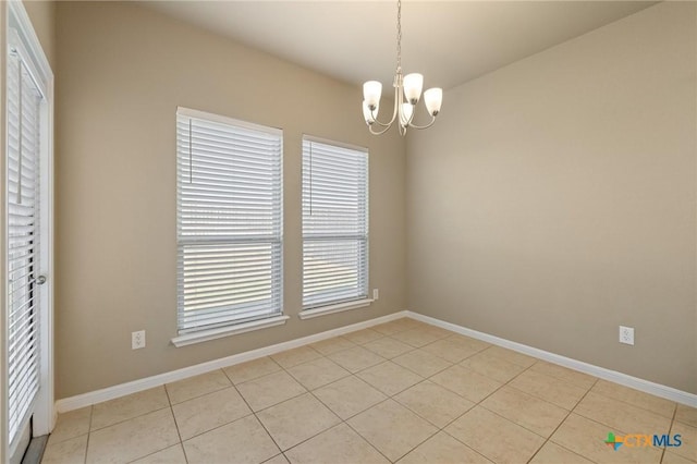 empty room with a chandelier, baseboards, and light tile patterned flooring