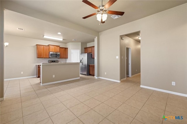 kitchen featuring stainless steel appliances, baseboards, brown cabinets, and light countertops