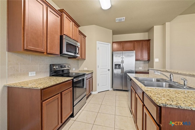 kitchen featuring visible vents, light tile patterned floors, decorative backsplash, appliances with stainless steel finishes, and a sink