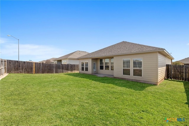 back of house featuring a yard, a fenced backyard, and roof with shingles