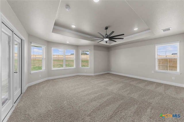 empty room with carpet, a tray ceiling, ceiling fan, and crown molding