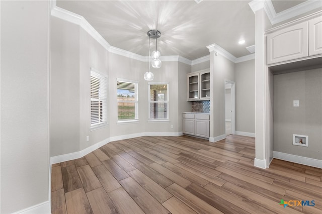 unfurnished dining area featuring light hardwood / wood-style flooring and ornamental molding