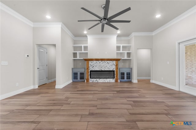 unfurnished living room with a tile fireplace, crown molding, light hardwood / wood-style flooring, and ceiling fan