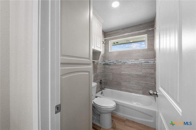 bathroom featuring tiled shower / bath combo, toilet, wood-type flooring, and a textured ceiling