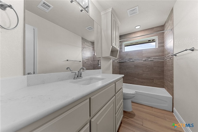 full bathroom with hardwood / wood-style floors, vanity, toilet, and tiled shower / bath