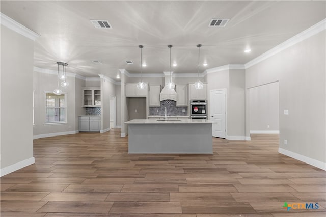 kitchen featuring white cabinets, decorative light fixtures, wood-type flooring, and backsplash