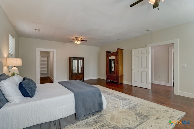 bedroom featuring a closet, a spacious closet, ceiling fan, and dark hardwood / wood-style floors