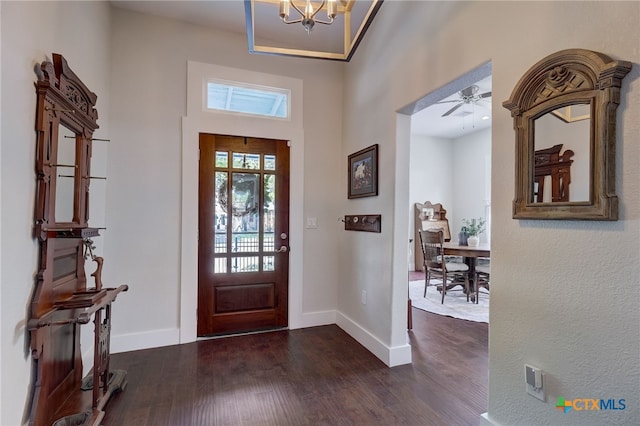 foyer with ceiling fan with notable chandelier and dark hardwood / wood-style flooring