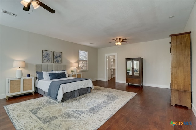 bedroom featuring ceiling fan, dark hardwood / wood-style floors, and a walk in closet