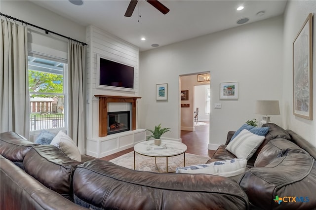 living room featuring wood-type flooring, a tile fireplace, and ceiling fan