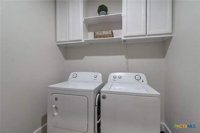 clothes washing area featuring separate washer and dryer and cabinets