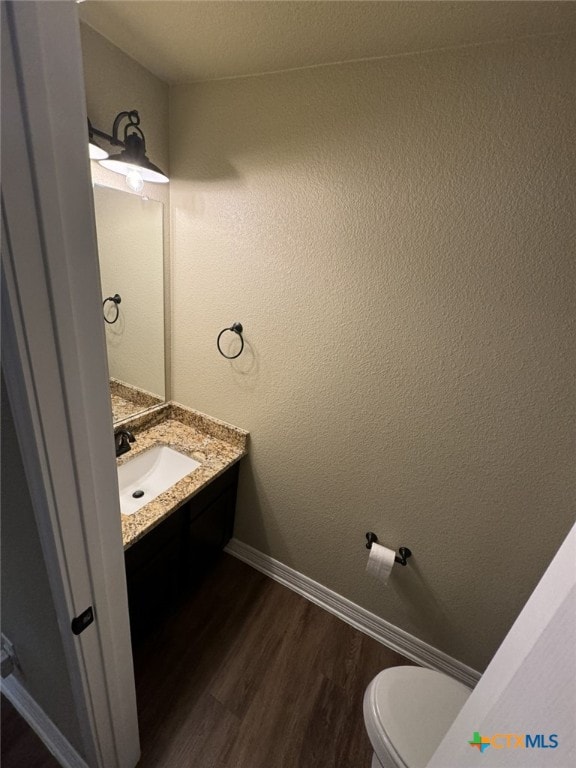 bathroom featuring toilet, vanity, and wood-type flooring