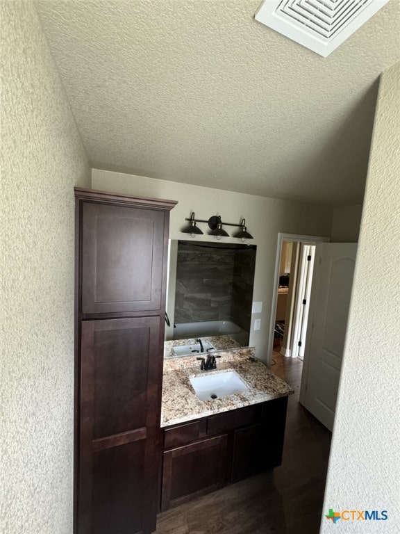 bathroom with hardwood / wood-style floors, vanity, and a textured ceiling