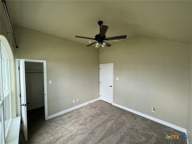 unfurnished bedroom with ceiling fan, carpet flooring, a spacious closet, lofted ceiling, and a closet