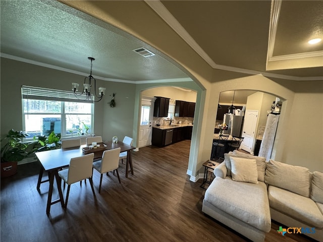 dining room with dark hardwood / wood-style floors, a textured ceiling, an inviting chandelier, and crown molding