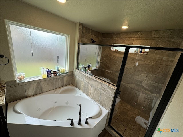 bathroom featuring shower with separate bathtub and a textured ceiling