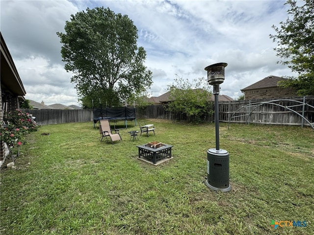 view of yard featuring a trampoline and a fire pit