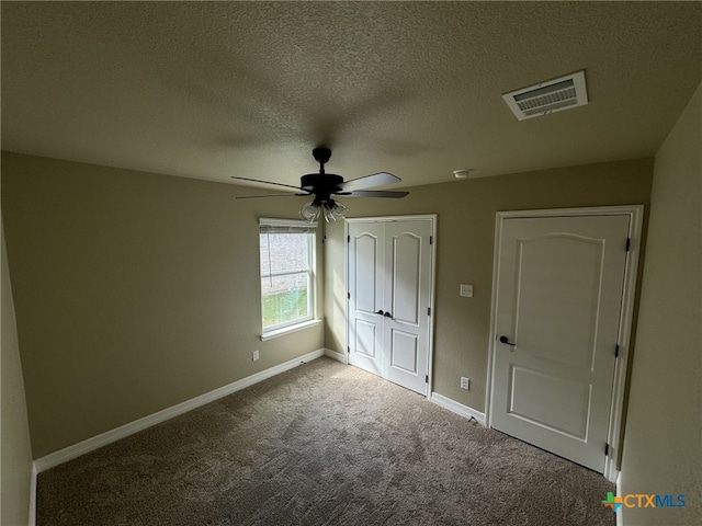 unfurnished bedroom featuring carpet, a textured ceiling, and ceiling fan