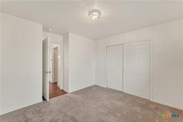 unfurnished bedroom featuring a textured ceiling, a closet, and carpet