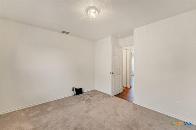 spare room featuring carpet floors, visible vents, and baseboards