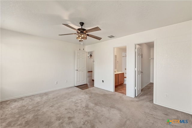 unfurnished bedroom featuring carpet, a spacious closet, visible vents, and a textured ceiling