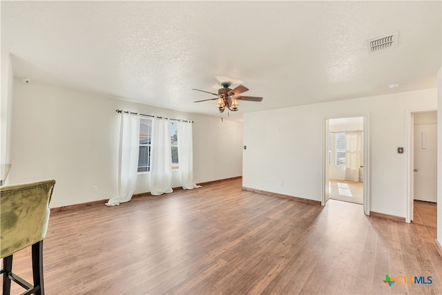 unfurnished living room with light hardwood / wood-style floors, a textured ceiling, and ceiling fan