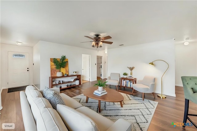 living room with wood finished floors, a ceiling fan, and baseboards