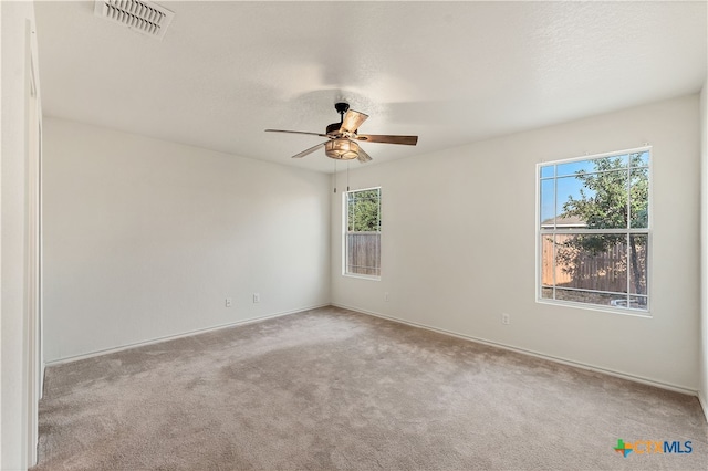 carpeted empty room featuring a textured ceiling, plenty of natural light, and ceiling fan