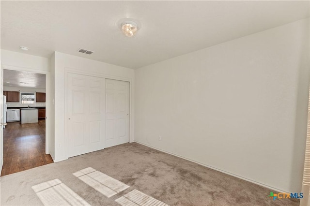 unfurnished bedroom featuring a closet, dark carpet, and visible vents