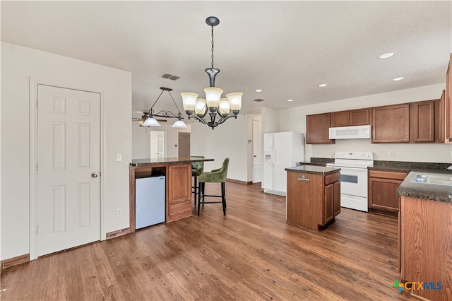 kitchen with white appliances, dark hardwood / wood-style floors, a chandelier, and decorative light fixtures