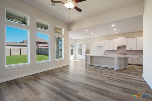 kitchen with white cabinets, tasteful backsplash, a kitchen island with sink, and light hardwood / wood-style flooring